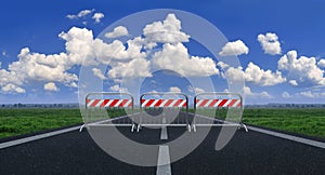 Metal barriers blocking a straight line against a blue sky with white clouds