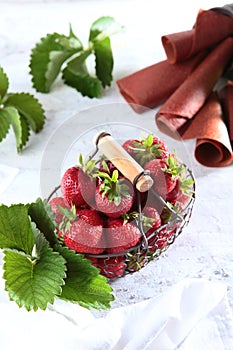 Metal basket with fresh strawberries. Strawberry pastille is rolled into a tube. Natural product. Copy of the space. Vertical