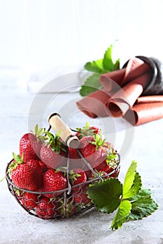 Metal basket with fresh strawberries. Strawberry pastille is rolled into a tube. Natural product. Copy of the space. Vertical