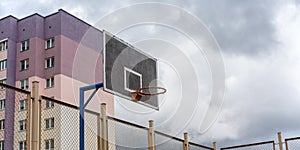 Metal basketball hoop located on local court with fence