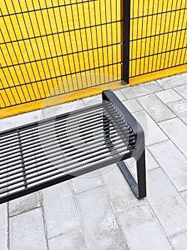 Metal bench near bright yellow playground