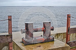 Metal berth for ships at sea. Rusty Mooring Bollard. Mooring in the port, with the sea in the background