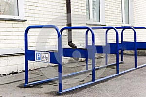 A metal bicycle park of blue color that stands in the city near