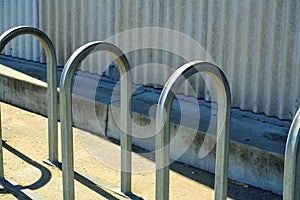 Metal bike rack arches for securing and chaining bicycle on side of metal building in urban downtown area of city