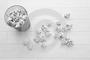 Metal bin and crumpled paper on floor, above view.