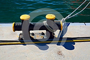 Metal bitt on a pier with a mooring line and a cabling in front