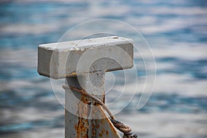 Metal bitts with a rope on the background of water