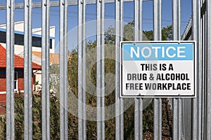 metal black, white and blue Notice, This is a Drug and Alcohol Free Workplace warning sign on the fence of an industrial workplace
