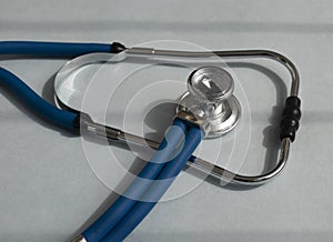 Metal blue sthethoscope on gray desk, close up photo