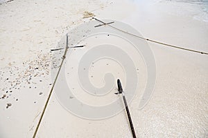 Metal boat anchors and ropes at sand