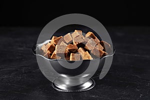 Metal bowl with brown sugar cubes on table
