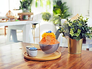 A metal bowl of Thai tea shaved ice topped with egg yolk floss served with condensed milk and Thai glutinous rice balls Bua Loi