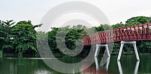 A metal bridge across a mountain river. Red iron bridge on a river near a forest