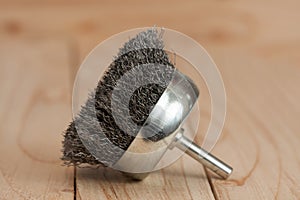 Metal brush on a drill to remove rust on a light wooden background