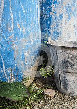 Metal bucket and blue plastic barrels used on construction sites