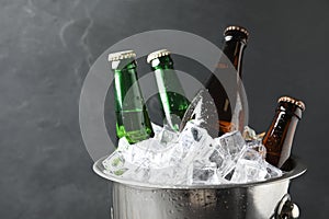 Metal bucket with bottles of beer and ice cubes on  background