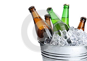Metal bucket with bottles of beer and ice cubes on white