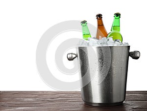 Metal bucket with bottles of beer and ice cubes on table against white background. Space for text