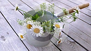 Metal bucket with a bouquet of daisies. Bath accessories and wildflowers on a wooden background