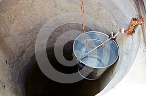 Metal bucket in draw-well in European village