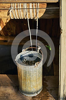 Metal bucket full of fresh water just taken up from a old wooden draw-well at countryside in a summer day