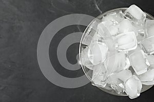 Metal bucket with ice cubes on background, top view. Space for text