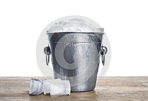 Metal bucket with ice cubes on table against white background