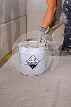 metal bucket is labeled with a corrosive sign and text to indicate that the contents are hazardous and potentially harmful to