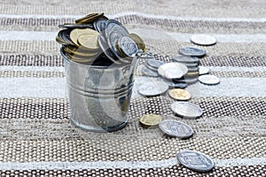 Metal bucket with pennies on coarse cloth.