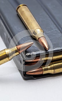 A metal 223 caliber rifle magazine loaded with 223 caliber bullets with two bullets on top of it