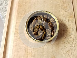 Metal can of bugs or insects on wood cutting board