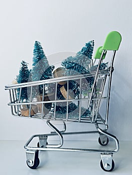 A metal cart for goods is filled with Christmas trees. In anticipation of the New Year and Christmas. Greeting card.