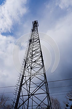 Metal cell of cellular communication against the background of the cloudy sky. Photo of a steel structure, close-up from below