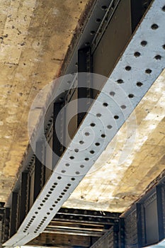 Metal and cement bridge girder and beam on the bottom of structure in shade with obvious rivets
