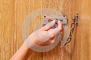 metal chain lock with hand on the wooden front door