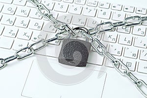 Metal chain and padlock close-up on the background of a white laptop keyboard