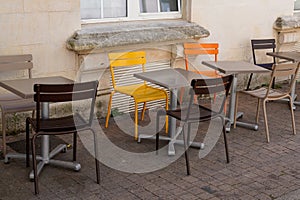 Metal chairs and tables in the street facing the restaurant bar terrace in street