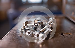 Metal chrome bolts and nuts lie on the shiny metal surface of the machine