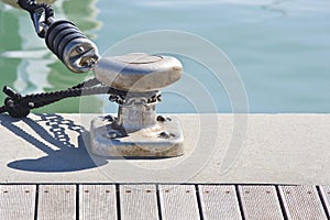 Metal cleat for mooring boats, bolted to the ground, with rope and shock absorber