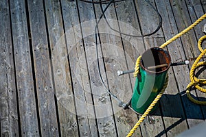 Metal cleat on wooden dock with mooring rope tied to it