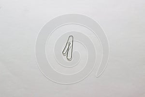 A metal clip in the form of the number one on a white sheet of Whatman paper. Paper clip isolate on a white background