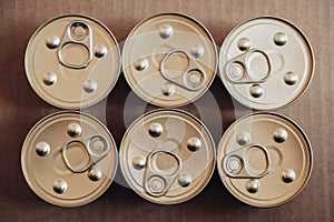 Metal closed canned food on a cardboard background. Top view. Copy, empty space for text