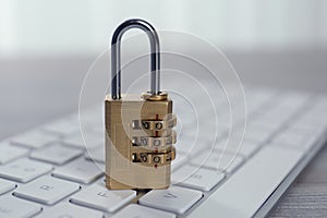 Metal code padlock and computer keyboard on table, closeup. Cyber security concept