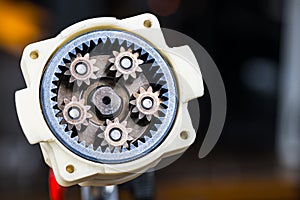 Metal cog wheels in open planetary gearbox of power drill on dark background