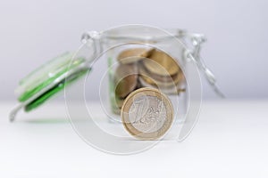 Metal coin of 1 euro, a jar with small change on a white background, close-up, selective focus.Concept: financial savings, expense