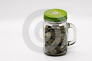 Metal coins in glass jar of mason jar on white background