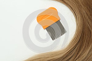 Metal comb and blond hair on white background, flat lay. Anti lice treatment