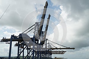 Metal construction of blue big gantry cranes in horizontal position awaiting cargo operation of the container ships.