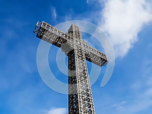 Metal construction christian cross with beautiful blue sky and cloudy background.