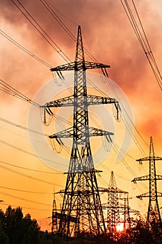 Metal construction silhouette. Electrical supply tower shadows on orange sunset.